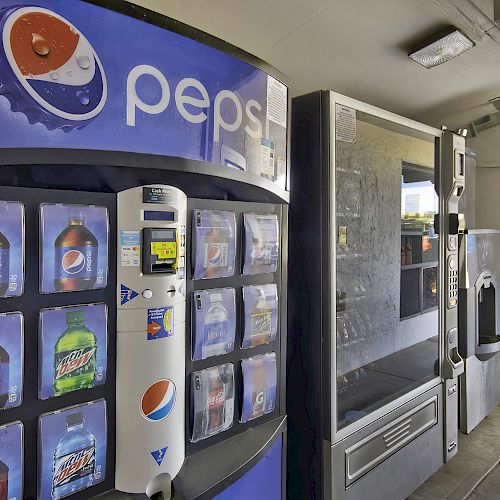 The image shows a row of vending machines, including one for Pepsi beverages, located in an outdoor area near a building.